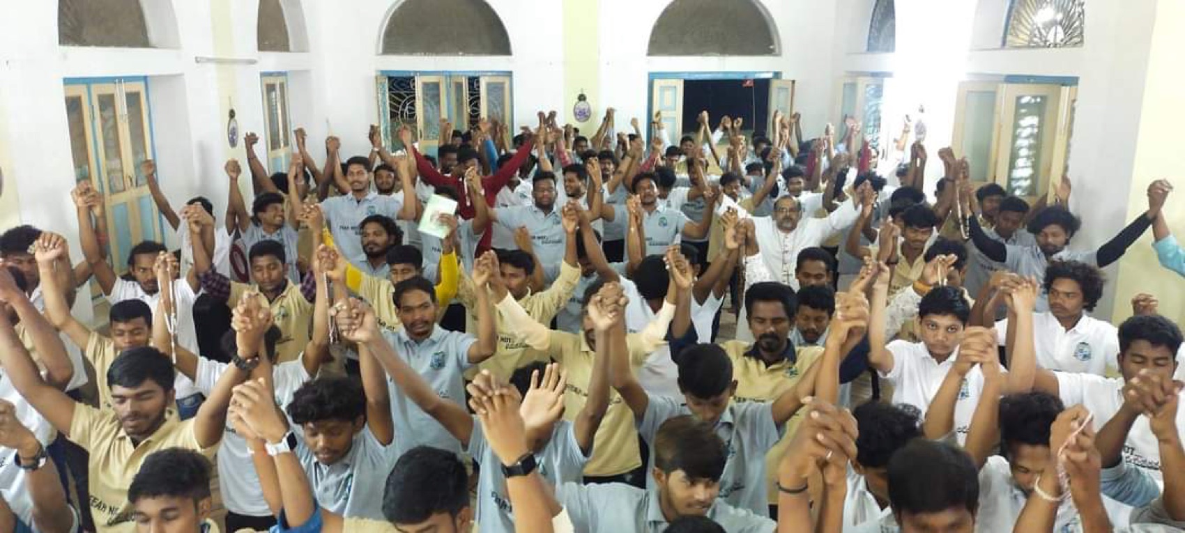 Hundreds of young people, hands raised in prayer at our youth gathering.